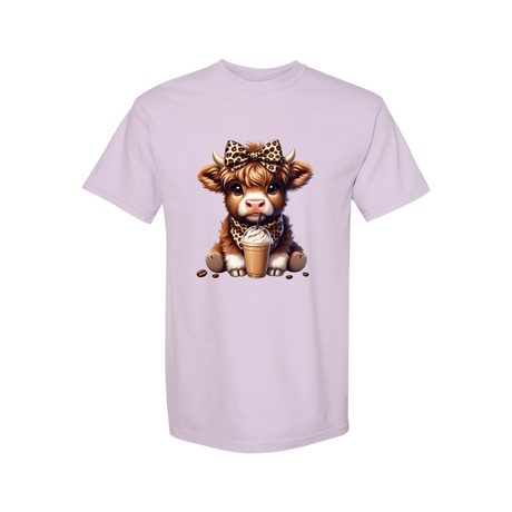 Dixie Magnolia Market light purple graphic tee with a cute Highland cow wearing a leopard print bow and bandana, holding an iced coffee.